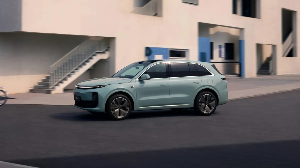 стильный кроссовер Li Auto L6 на фоне гор Заилийского Алатау, солнечный день, автомобиль цвета "зеленый металлик" с включенной футуристичной световой полосой
