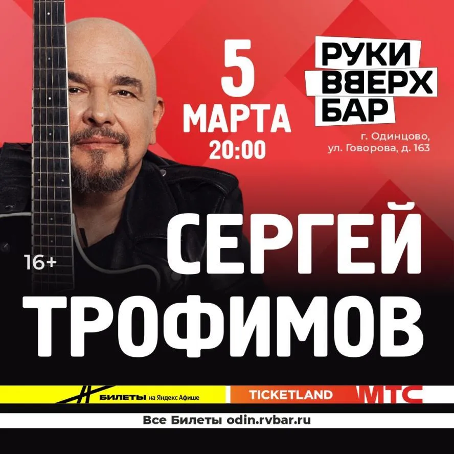 атмосферный портрет Сергея Трофимова с гитарой на фоне теплого сценического света, создающий ощущение уютного квартирника или доверительного разговора по душам